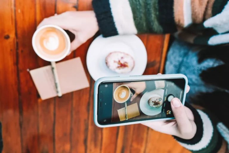 Person photographing coffee and pastry.